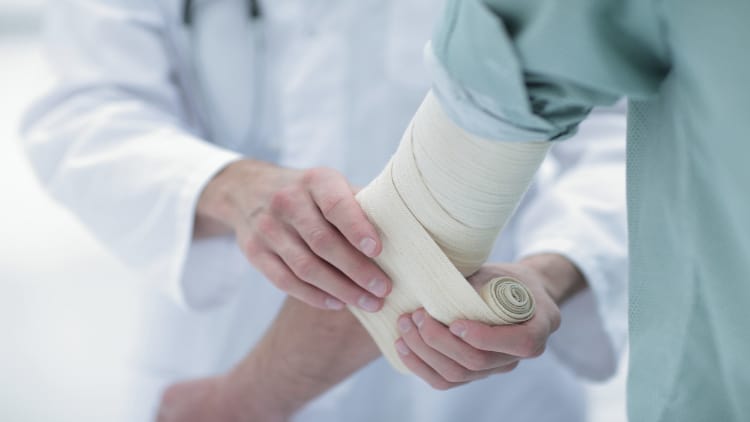 A doctor wrapping a patient's elbow in a bandage