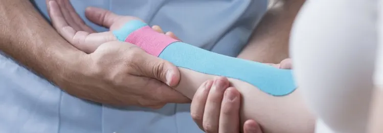 Physiotherapist putting kinesiology tape on a person's forearm