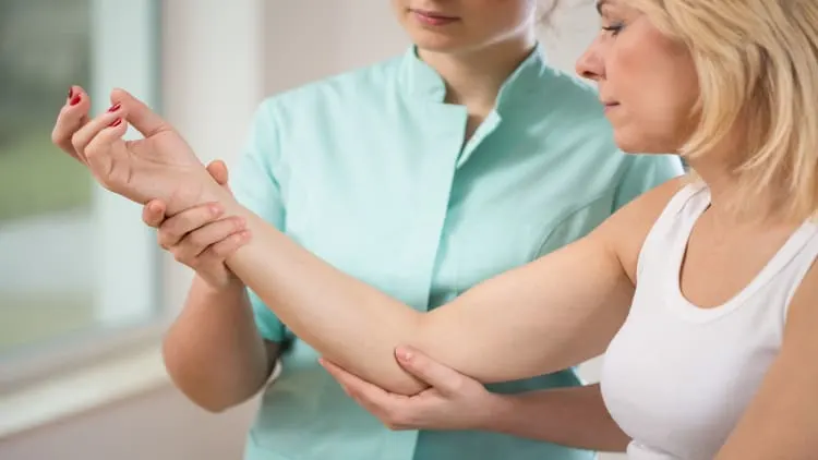 Physiotherapist flexing a patient's elbow