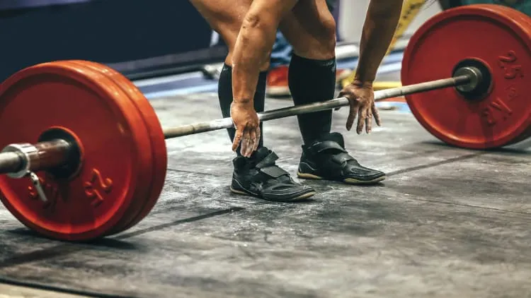 Powerlifting gripping a barbell in preperation for the deadlift