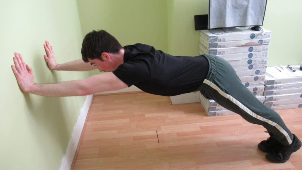 A man performing against the wall tricep extensions