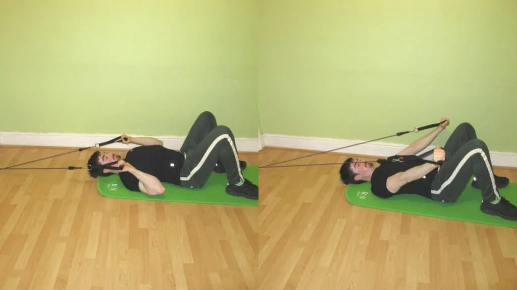 A man performing a banded French press on the floor