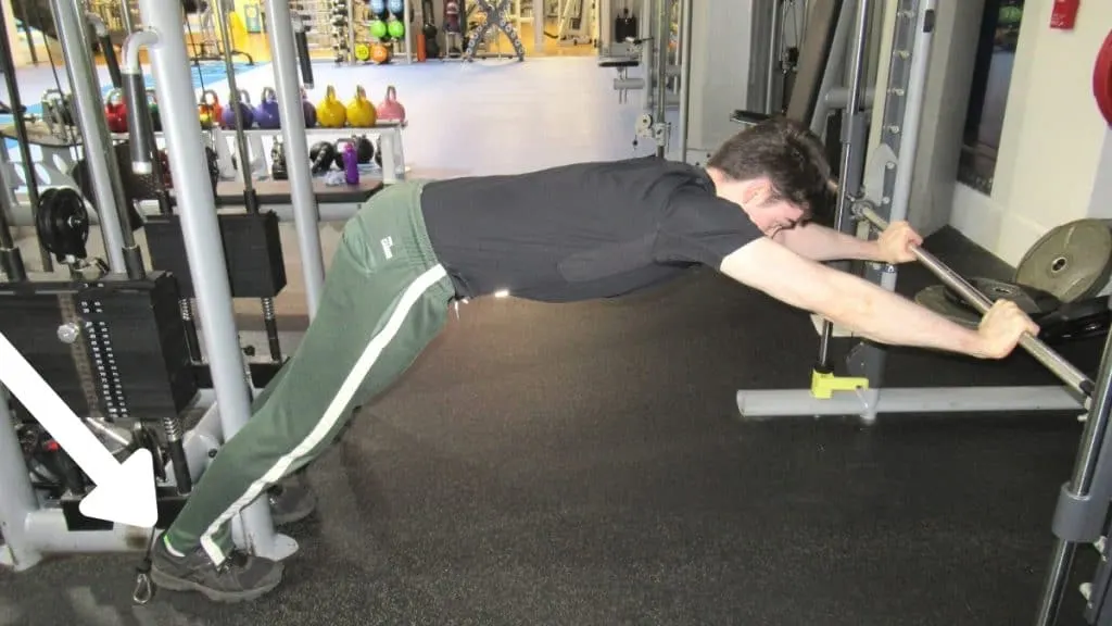 A man doing a fixed bar triceps extension at the gym