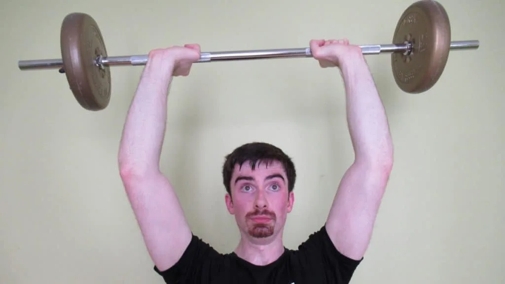 A man doing overhead bar extensions for his triceps