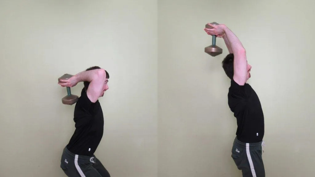 A man using momentum to lift the dumbbell during an overhead standing tricep extension