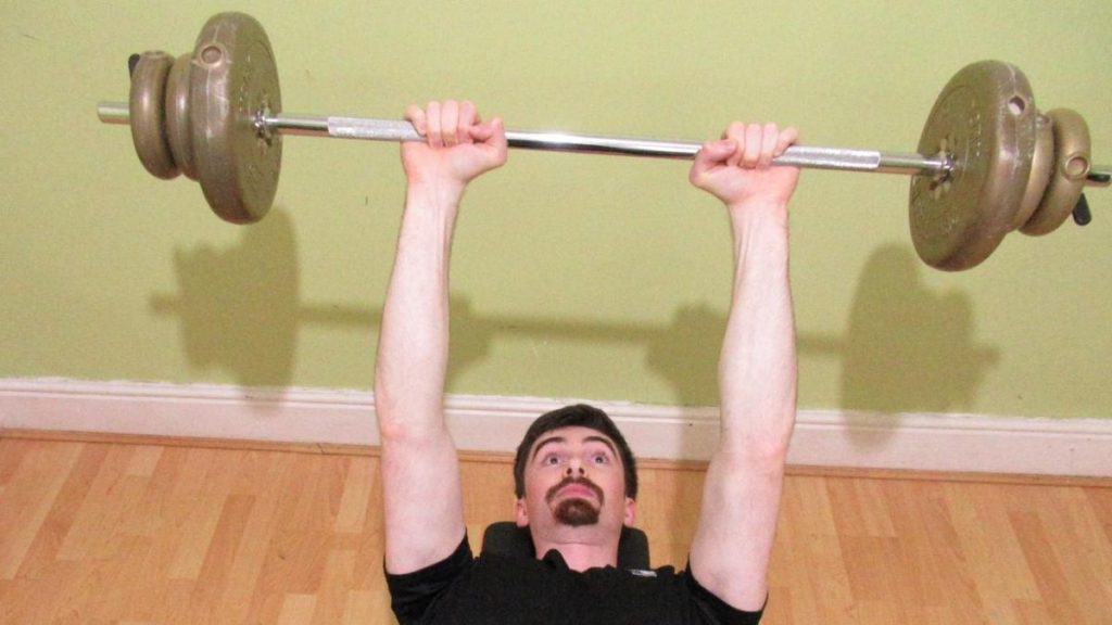 A man performing a lying barbell triceps extension