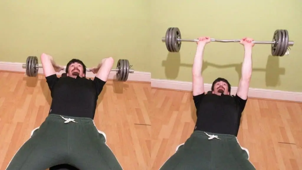 A man doing lying cambered bar extensions for his triceps