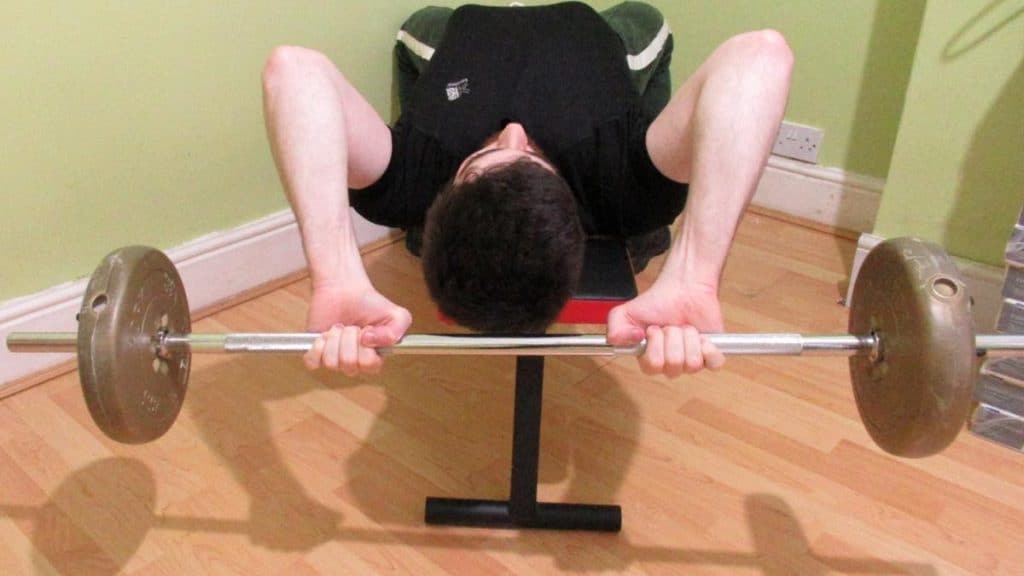 A man performing a lying tricep extension with a barbell