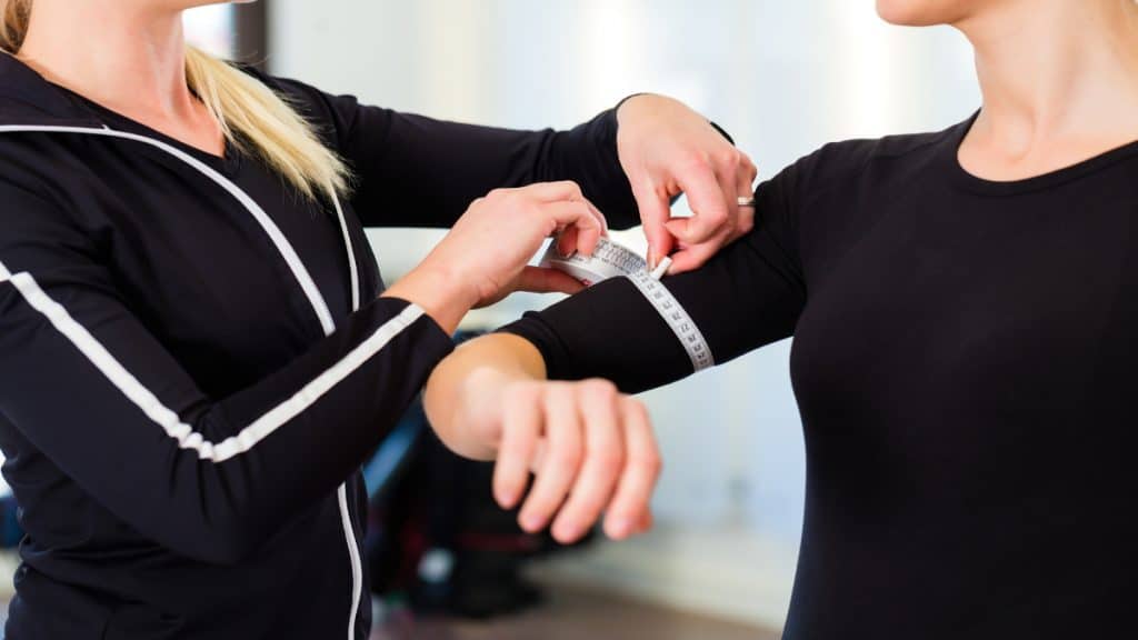 A woman getting her 12 in arms measured by her coach