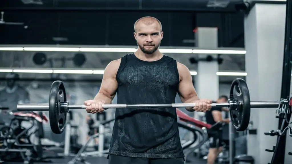 A man performing a 135 lb barbell curl for his biceps