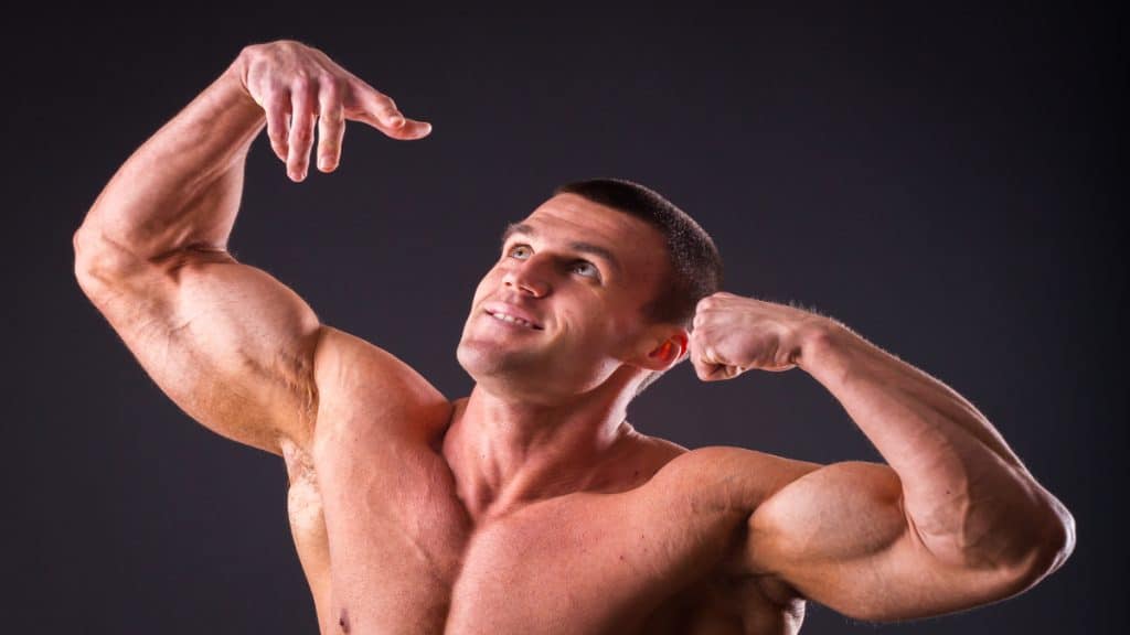 A bodybuilder flexing his arms because he's in the 20 inch biceps club