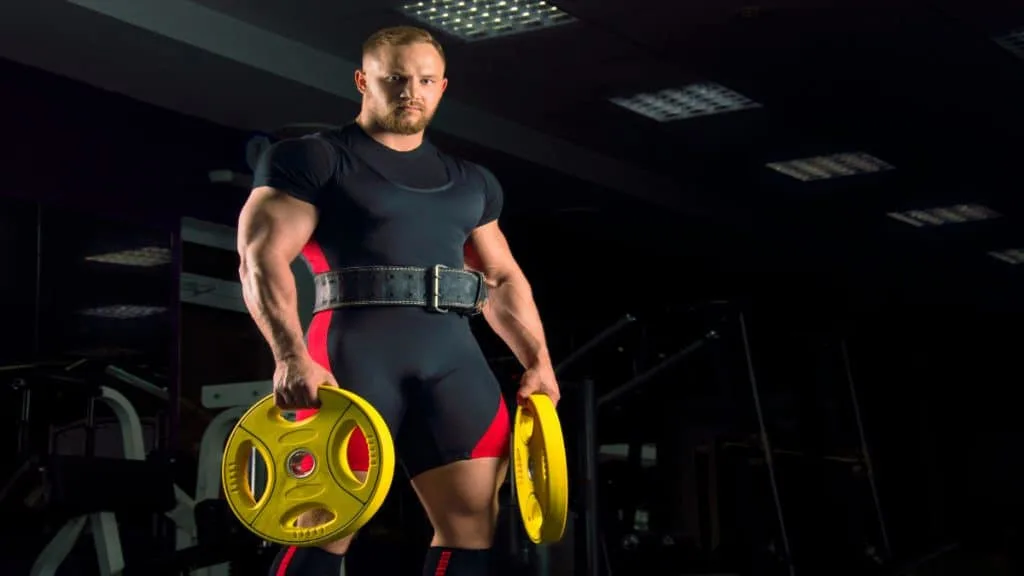 A weight lifter with 22 inch arms holding some plates