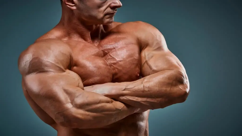 A bodybuilder folding his arms and displaying his 22 inch bicep muscles