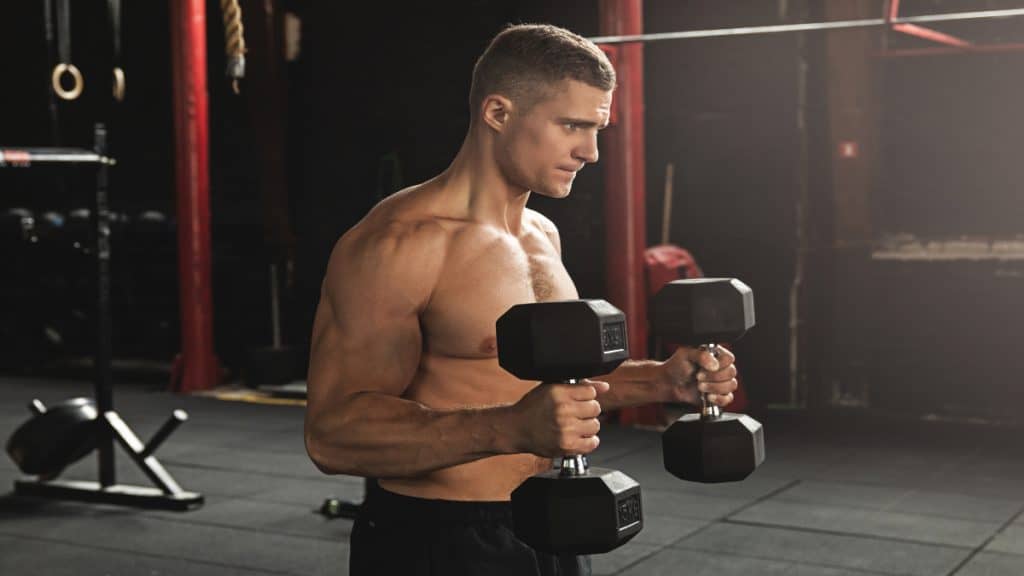 A man doing 25 lb dumbbell curls at the gym to train his biceps