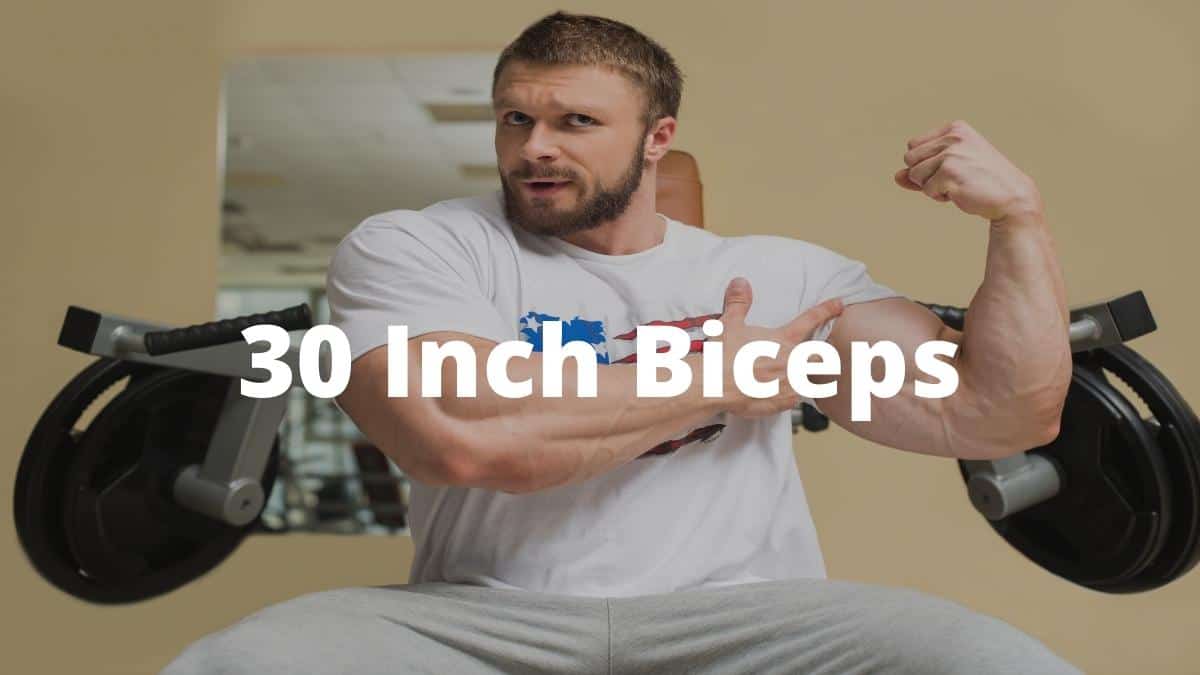 A bodybuilder pointing at his 30 inch biceps