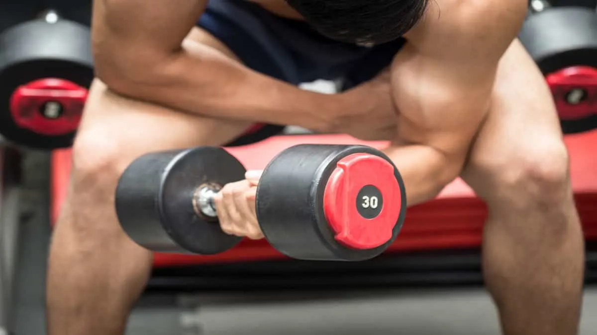 A man performing a 30 lb dumbbell curl to work his biceps