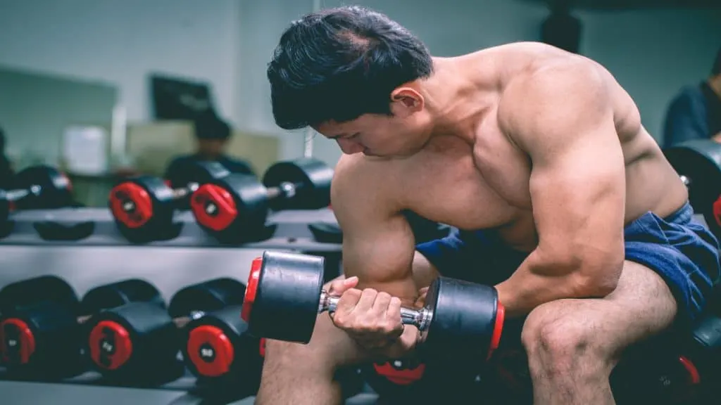 A man performing a 30 pound dumbbell curl for his biceps