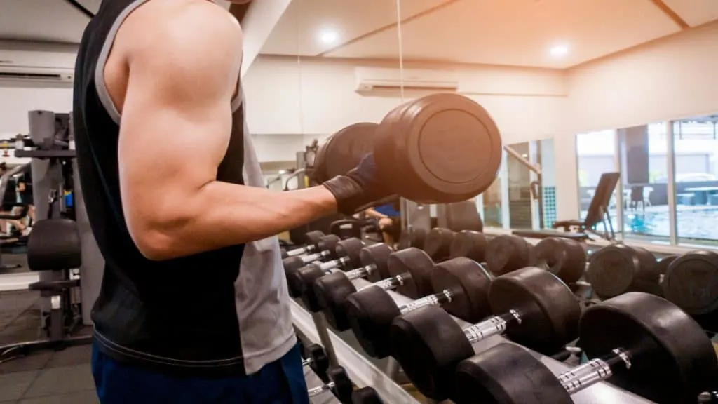 A man doing 35 lb dumbbell curls in the gym