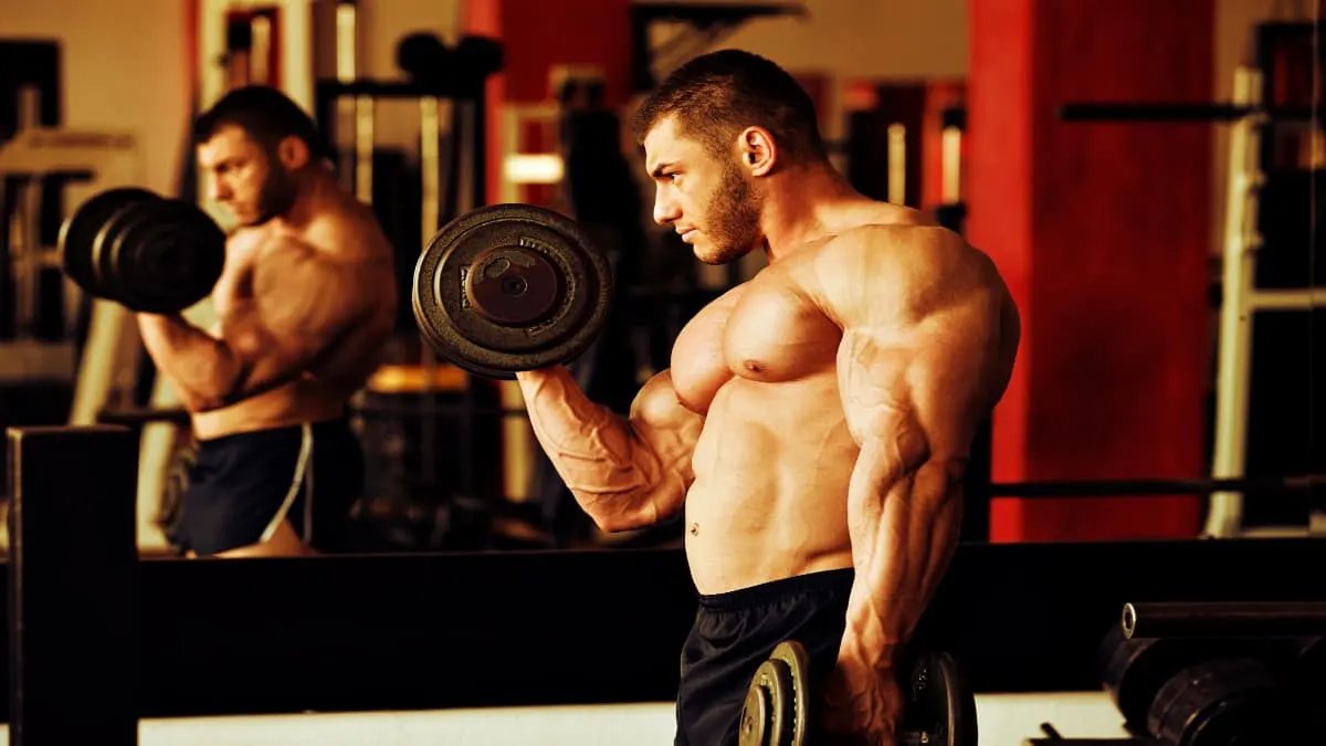 A bodybuilder performing 45 lb dumbbell curls for his biceps