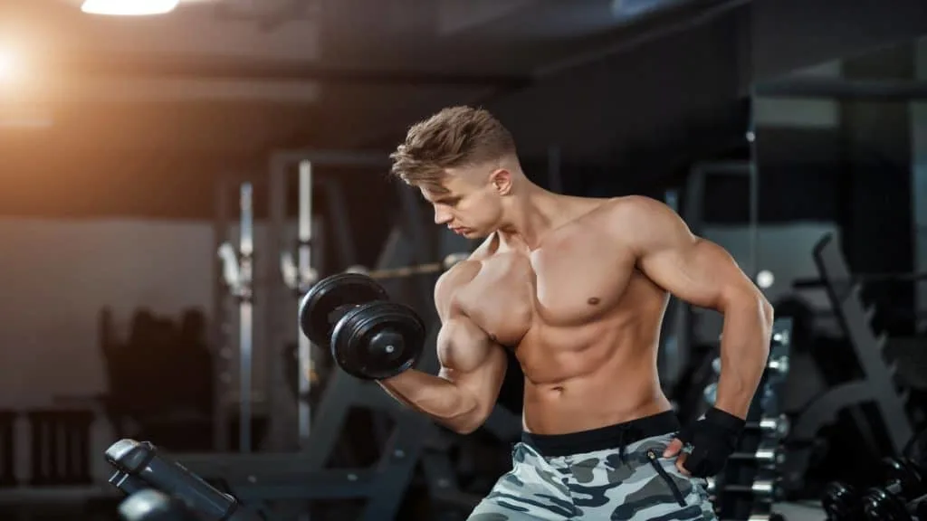 A muscular man doing 45 pound dumbbell curls for his biceps