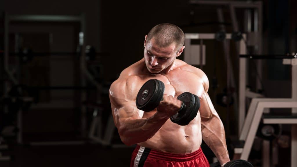 A muscular man performing a 50 lb dumbbell curl for his biceps