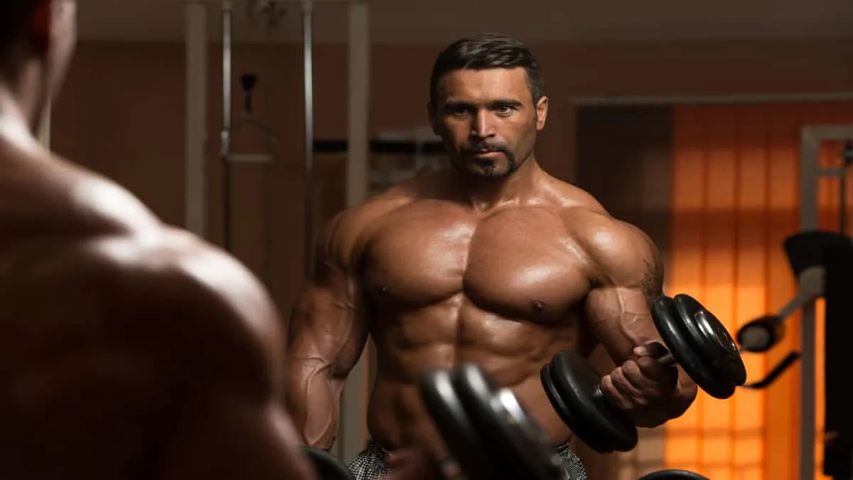 A bodybuilder doing a 60 pound dumbbell curl for his biceps