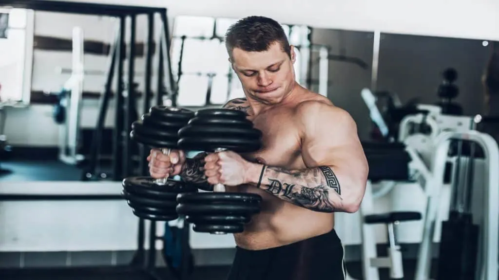 A muscular man doing 65 lb dumbbell curls