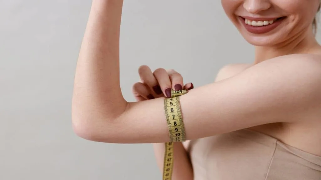 A woman measuring her 8 inch arms