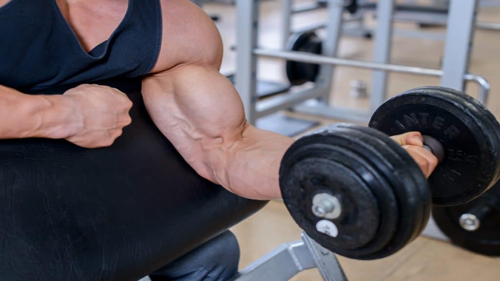 A muscular man doing an 80 pound dumbbell curl for his biceps