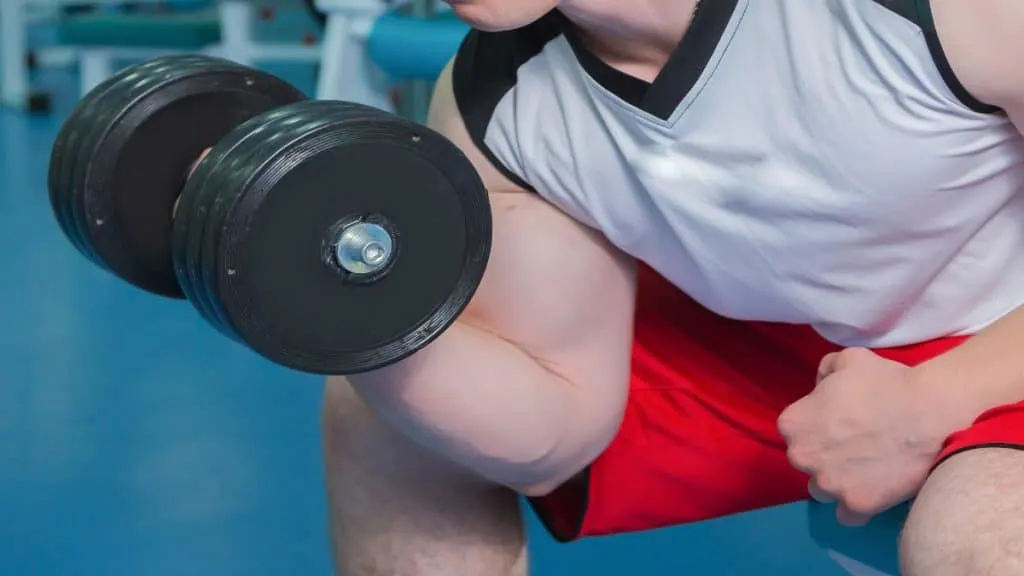 A muscular man performing a 90 lb bicep curl with a dumbbell