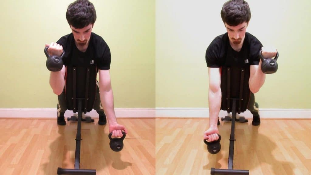 A man doing alternating spider curls with kettlebells