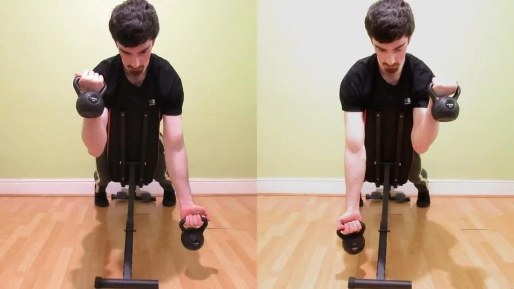 A man doing alternating spider curls with kettlebells