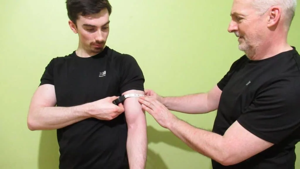 Two men figuring out the average male bicep size with a tape measure