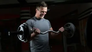 A man bicep curling 100 pounds with a barbell
