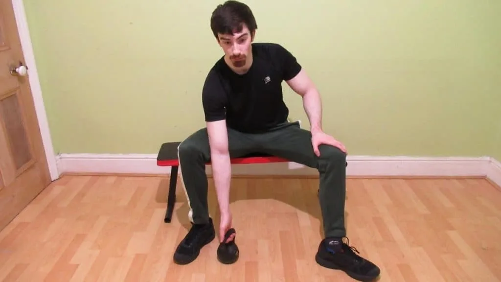 A man doing a concentration curl with a kettlebell