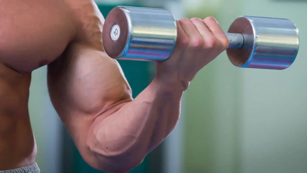 A muscular man bicep curling 10 pounds with a dumbbell