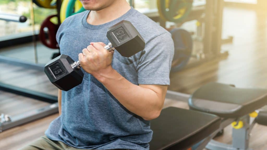 A man at the gym bicep curling 15 pounds with dumbbells