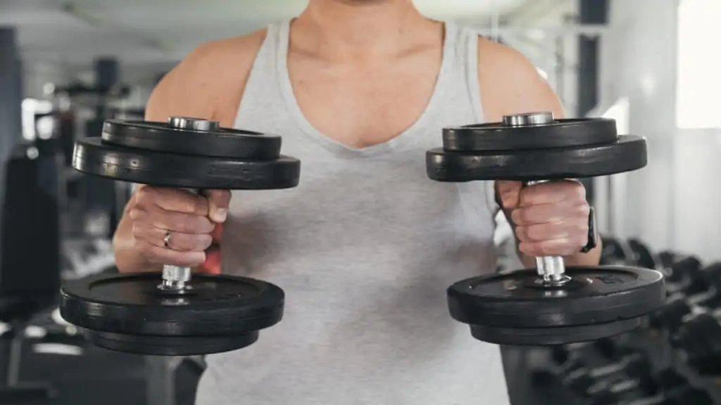 A man curling 50 lb dumbbells to train his biceps