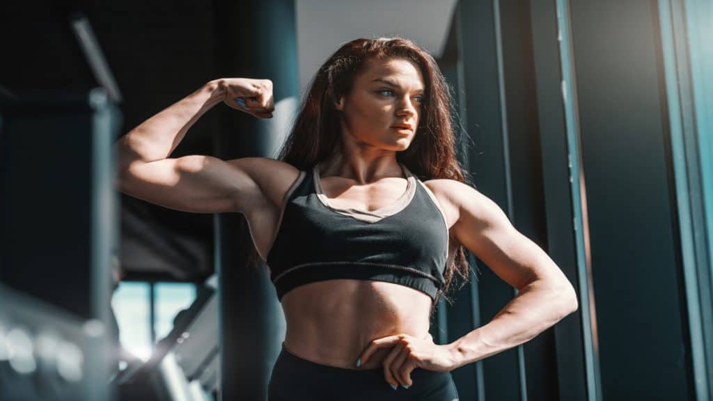 A female bodybuilder flexing her huge FBB biceps in the gym
