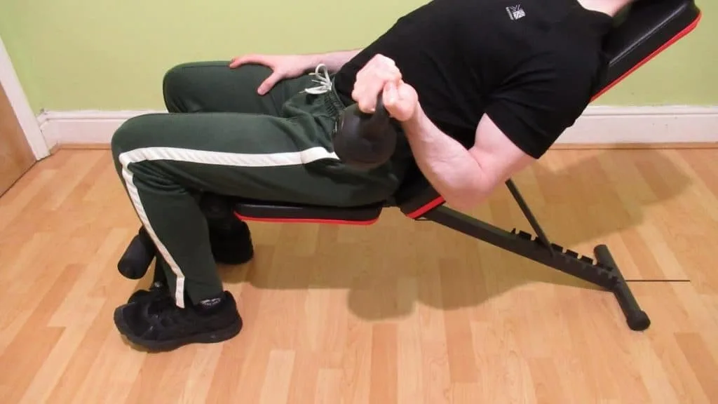 A man performing an incline curl with a kettlebell