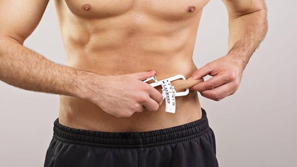 A man measuring his body fat with a caliper