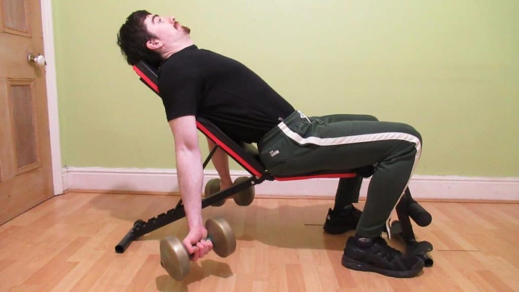 A man performing seated incline curls on a bench for his biceps