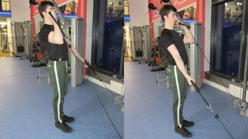 A man performing a standing alternate cable curl for his biceps