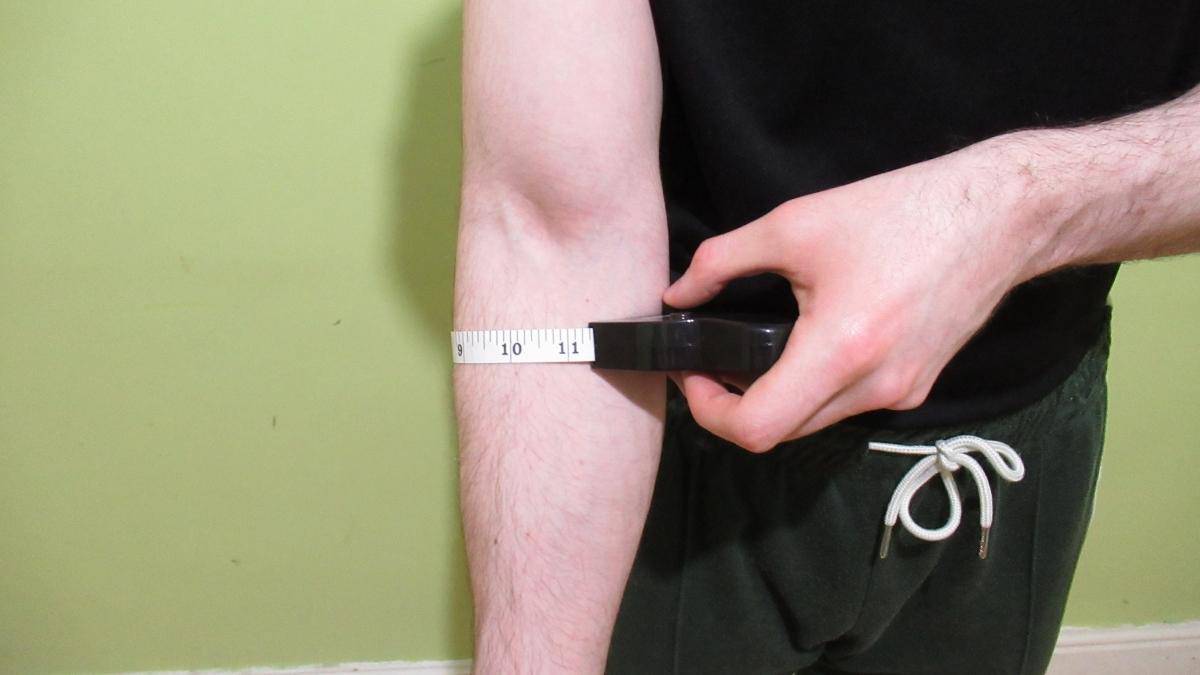 A man measuring his 11 inch forearms