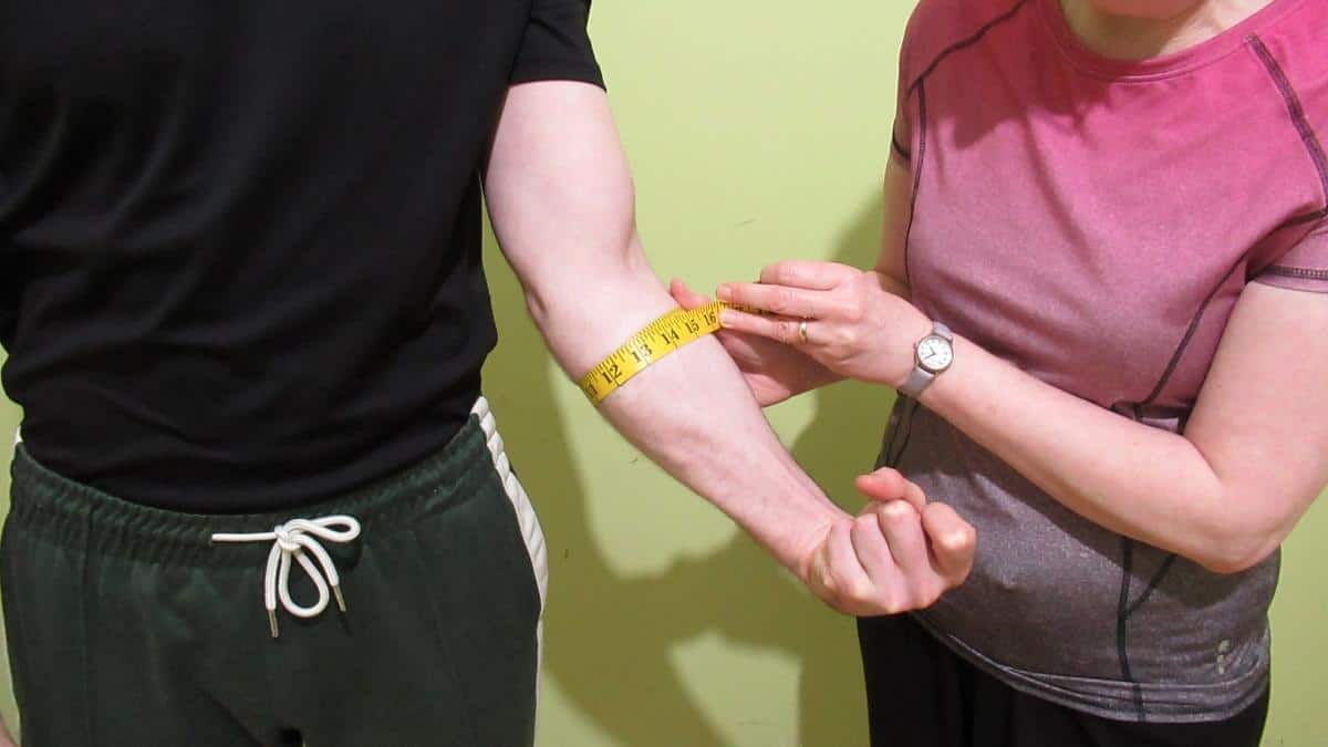 A man having his 13 inch forearms measured and verified by tape