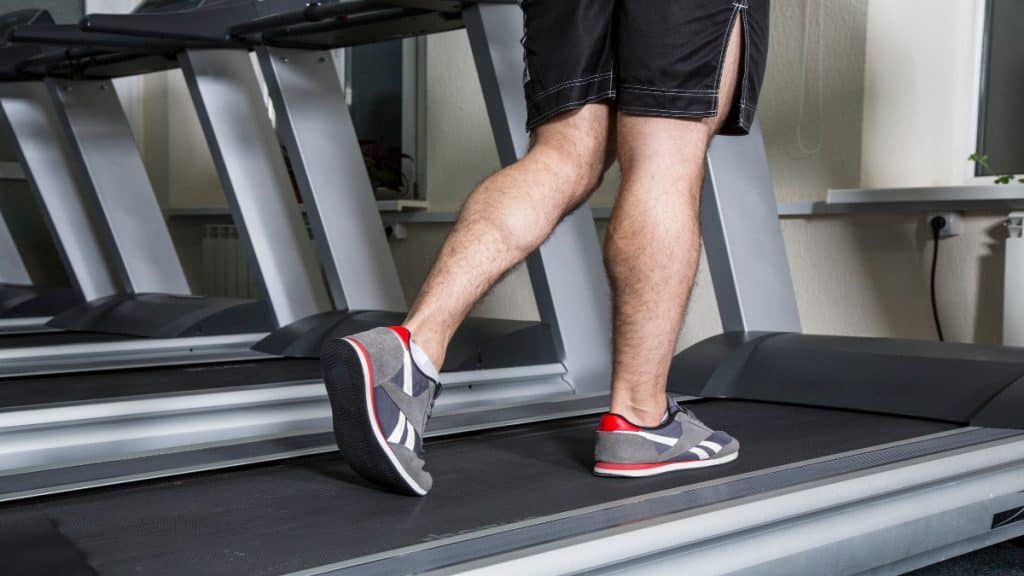 A man walking on the treadmill, showing his 14 inch calves