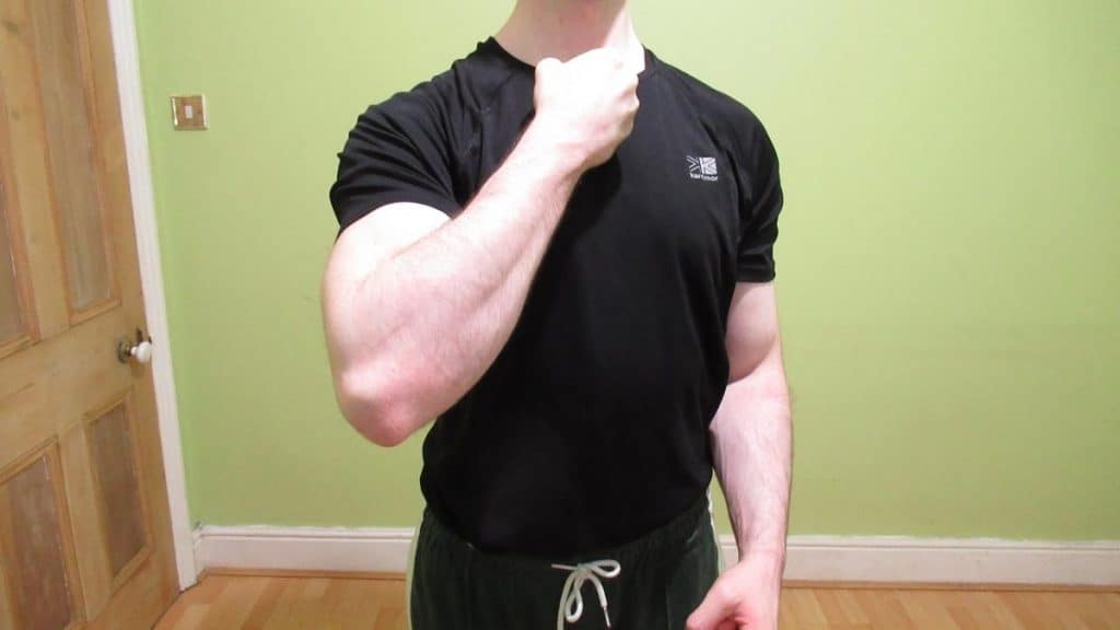 A man showing his 14 inch forearm