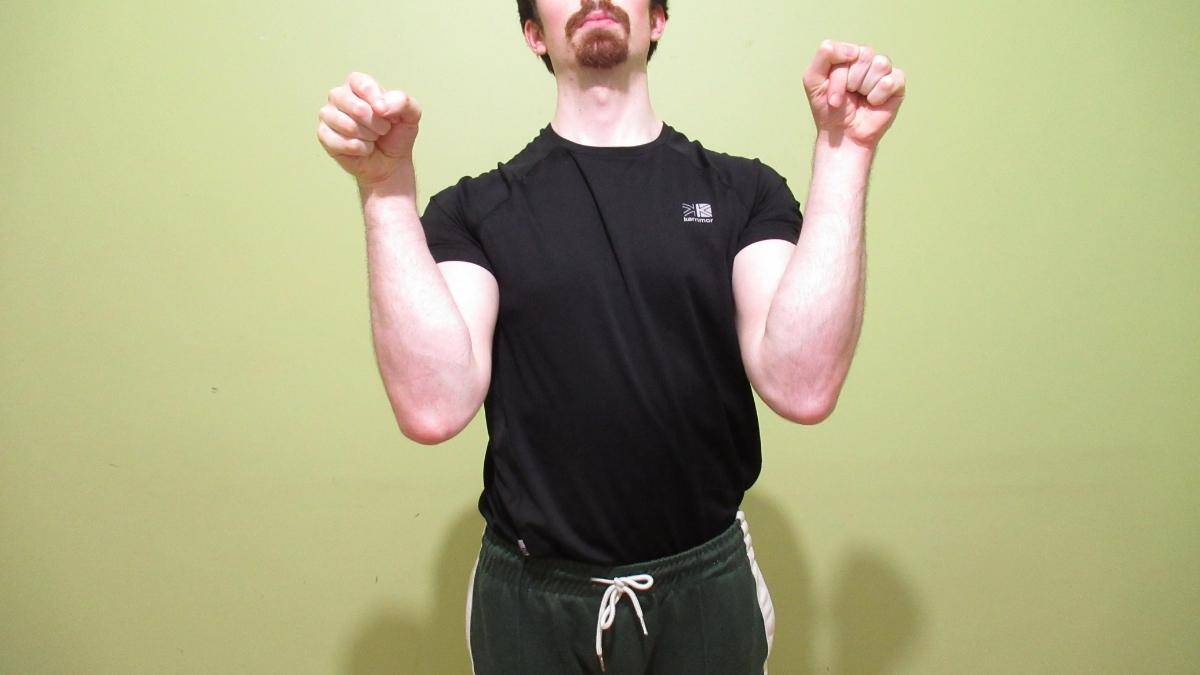 A muscular man displaying his impressive 14 inch forearms
