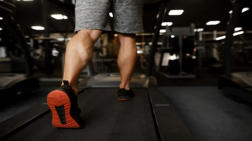 A man with 18 inch muscular calves walking on the treadmilll