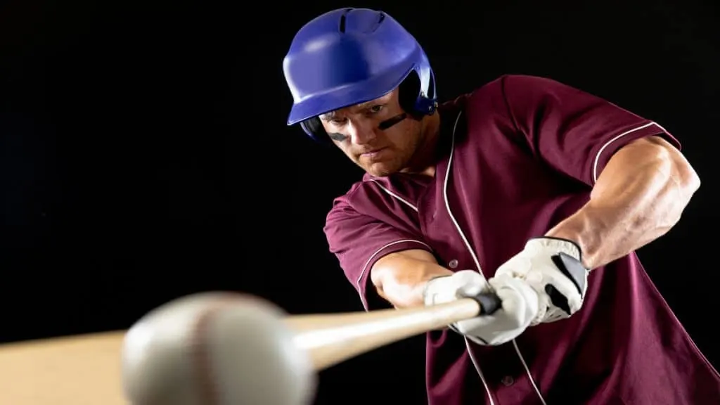 A baseball player's muscular forearms holding a bat